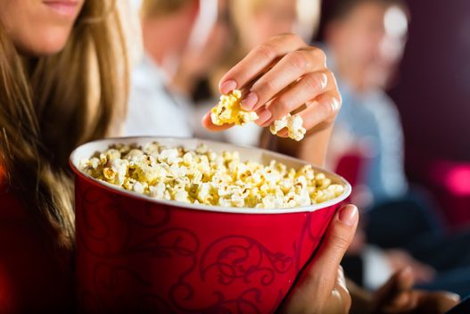 Kvinde der spiser popcorn i en biograf